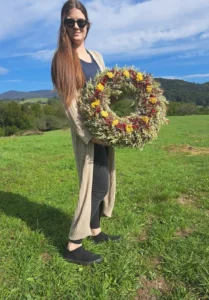 Zena drzi rucne viazany suseny kvetinovy venec na lake